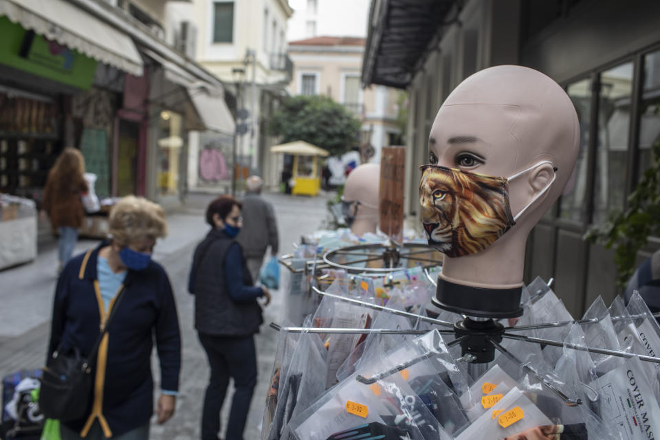 Women walk past a dummy wearing a face mask, in central Athens, Thursday, Oct. 29, 2020. Greece is seeing a record-breaking jump in the number of confirmed COVID-19cases for the second consecutive day, with 1,547 new cases announced Wednesday, Oct 28, and 10 new deaths. (AP Photo/Petros Giannakouris)