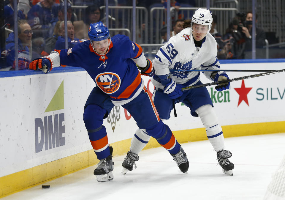 New York Islanders defenseman Scott Mayfield and Toronto Maple Leafs forward Tyler Bertuzzi battle for the puck during the first period of an NHL hockey game, Monday, Dec. 11, 2023, in New York. (AP Photo/John Munson)