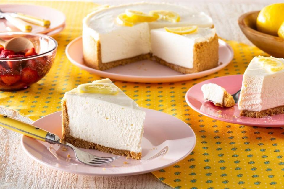 no bake lemon cheesecake slice on plate in front with whole cake in back