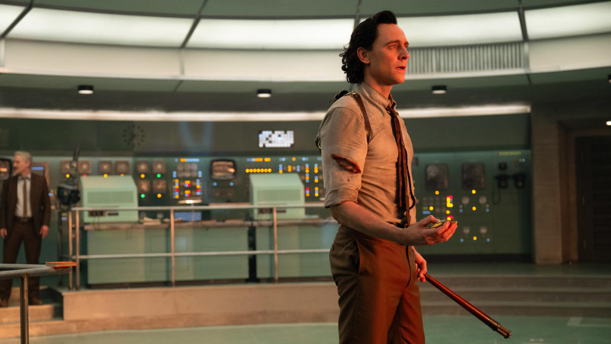  Loki holds a watch and TVA prune stick as he looks at the Temporal Loom in Loki season 2. 