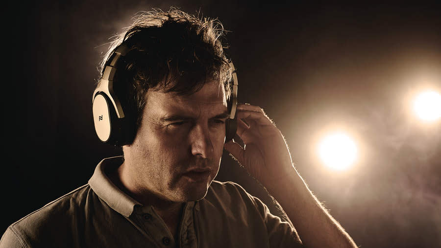  Man wearing a set of headphones on a dark background. 