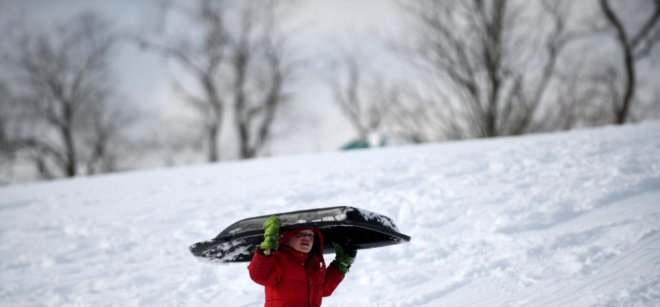 Henry Steele, 6, from Louisville, treks up the hill Saturday at Veterans Community Park in Plain Township while sledding with his family.