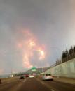 Smoke fills the air as people drive on a road in Fort McMurray, Alberta on Tuesday May 3, 2016 in this image provide by radio station CAOS91.1. THE CANADIAN PRESS/HO-CAOS91.1(KAOS)