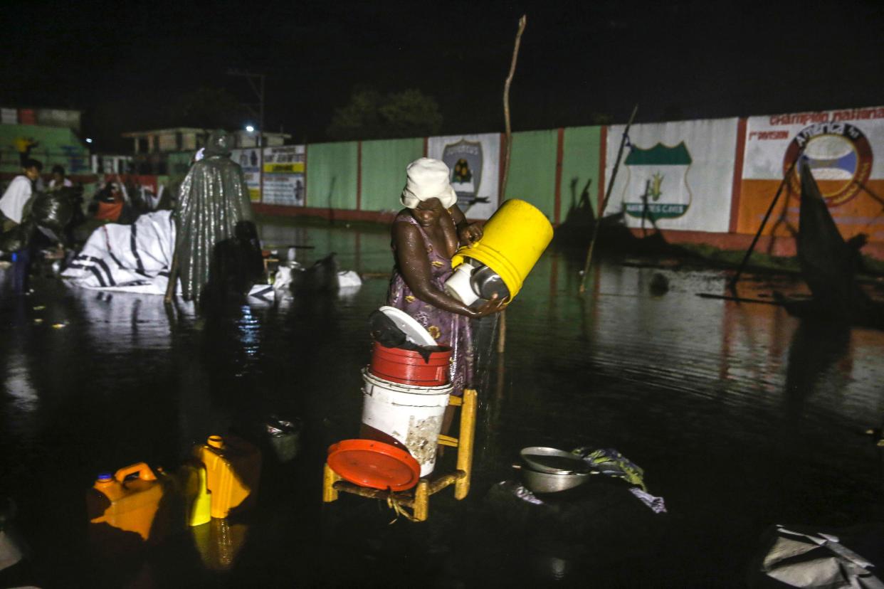 A woman affected by Saturday's earthquake recovers her belongings under the rain of Tropical Depression Grace at a refugee camp in Les Cayes, Haiti, Monday, Aug. 16, 2021.