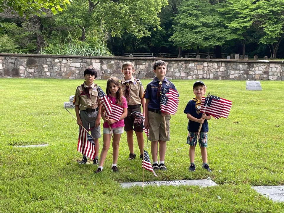 Scouts and siblings place flags on the graves of veterans at Pleasant Forest Cemetery, Memorial Day Monday, May 30, 2022.