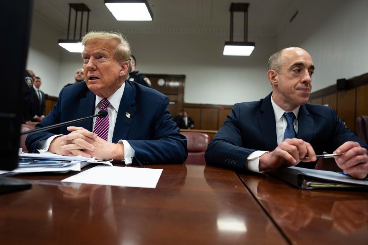 Donald Trump sits left in a suit next to his attorney.