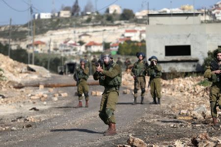 An Israeli soldier aims his weapon towards Palestinian protesters during clashes following a protest against the near-by Jewish settlement of Qadomem, in the West Bank village of Kofr Qadom near Nablus February 10, 2017. REUTERS/Mohamad Torokman