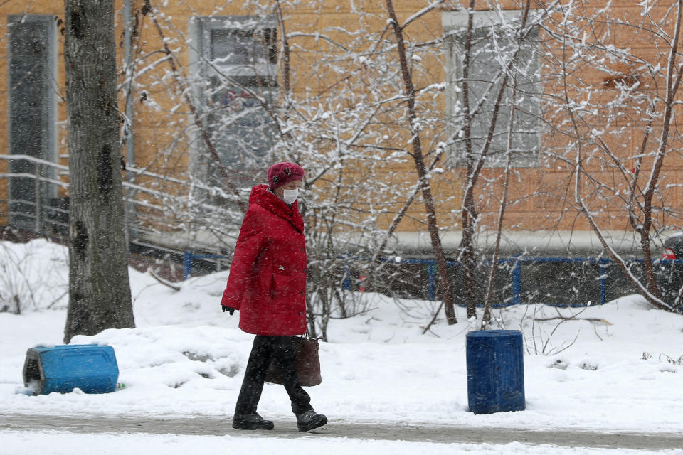 Photo shows a woman in a face mask and warm winter clothes walking in the snow in Yekaterinburg, Russia.