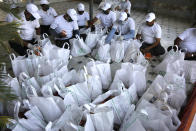 Indian volunteers makes essential item's kit to distribute to the needy people in Ahmedabad, India, Sunday, March 29, 2020. Indian Prime Minister Narendra Modi apologized to the public on Sunday for imposing a three-week national lockdown, calling it harsh but "needed to win" the battle against the coronavirus pandemic. The new coronavirus causes mild or moderate symptoms for most people, but for some, especially older adults and people with existing health problems, it can cause more severe illness or death. (AP Photo/Ajit Solanki)