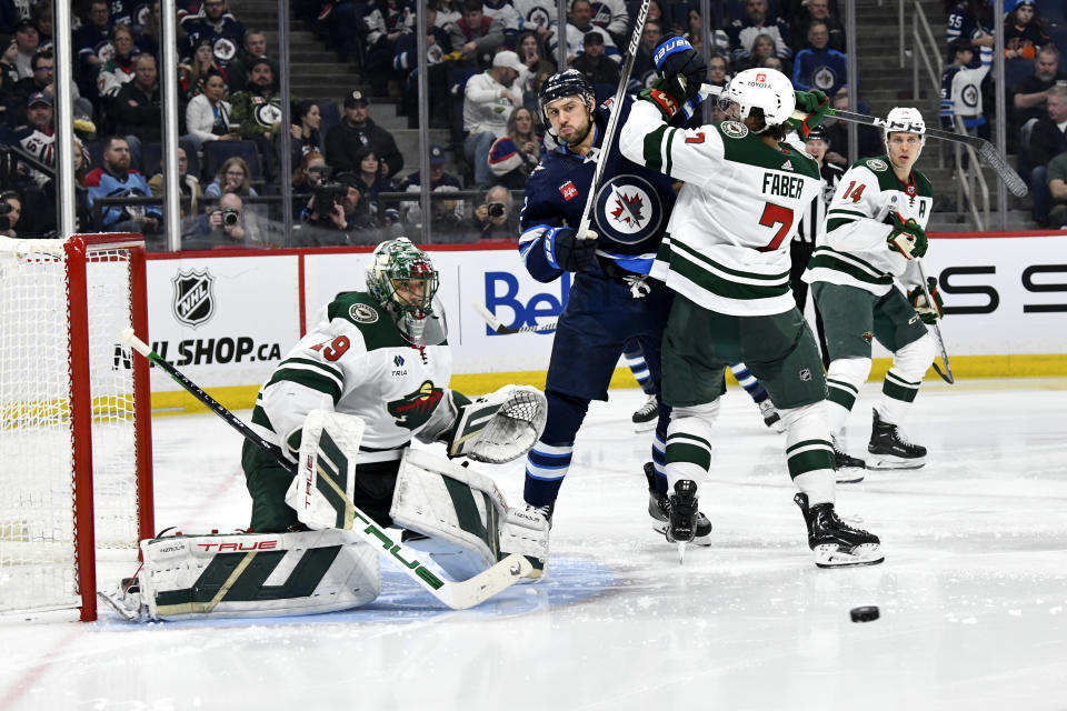 Minnesota Wild's Brock Faber (7) checks Winnipeg Jets' Nino Niederreiter (62) as a shot comes in on Wild goaltender Marc-Andre Fleury (29) during the second period of an NHL hockey game Tuesday, Feb. 20, 2024, in Winnipeg, Manitoba. (Fred Greenslade/The Canadian Press via AP)