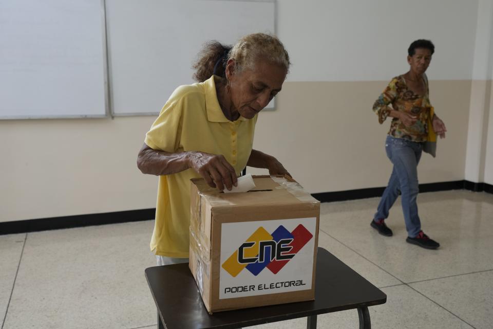 A woman places her electronic voting receipt into a ballot box as she participates in a voting rehearsal for the upcoming December referendum for the territorial dispute between Guyana and Venezuela in Caracas, Venezuela, Sunday, Nov. 19, 2023. (AP Photo/Ariana Cubillos)