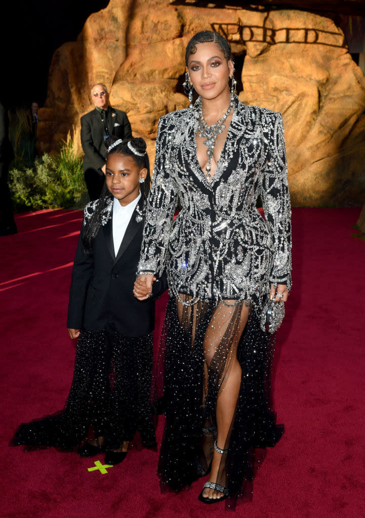 Beyoncé wears a long sleeve sparkly dress with a sheer skirt and Blue Ivy wears a dark suit dress