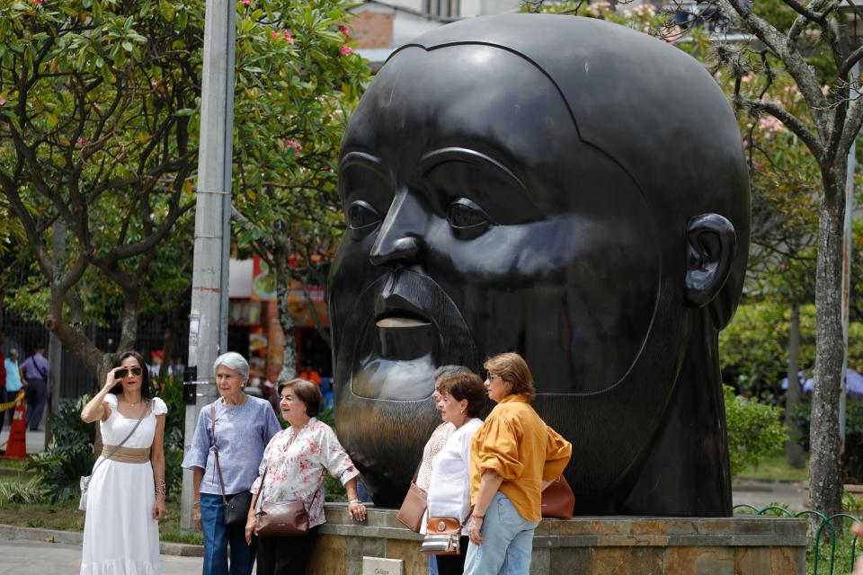 People pose for photos in front of a sculpture by Colombian artist Fernando Botero at Botero Park in Medellin, Colombia, on Sept. 15, 2023.