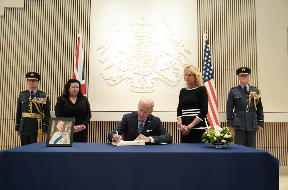 President Joe Biden signs the condolence book at the British Embassy in Washington to pay his respects following the death of Britain's Queen Elizabeth II as First Lady Jill Biden and British ambassador Karen Pierce watch.