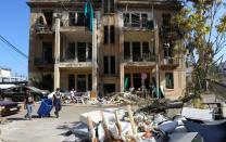 People walk near a damaged building following Tuesday's blast in Beirut's port area