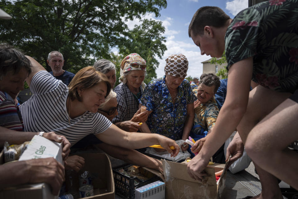 FILE - People receive humanitarian aid in the flooded village of Afanasiyevka, Ukraine, on June 15, 2023. Two years after Russia’s full-scale invasion captured nearly a quarter of the country, the stakes could not be higher for Kyiv. After a string of victories in the first year of the war, fortunes have turned for the Ukrainian military, which is dug in, outgunned and outnumbered against a more powerful opponent. (AP Photo/Evgeniy Maloletka, File)