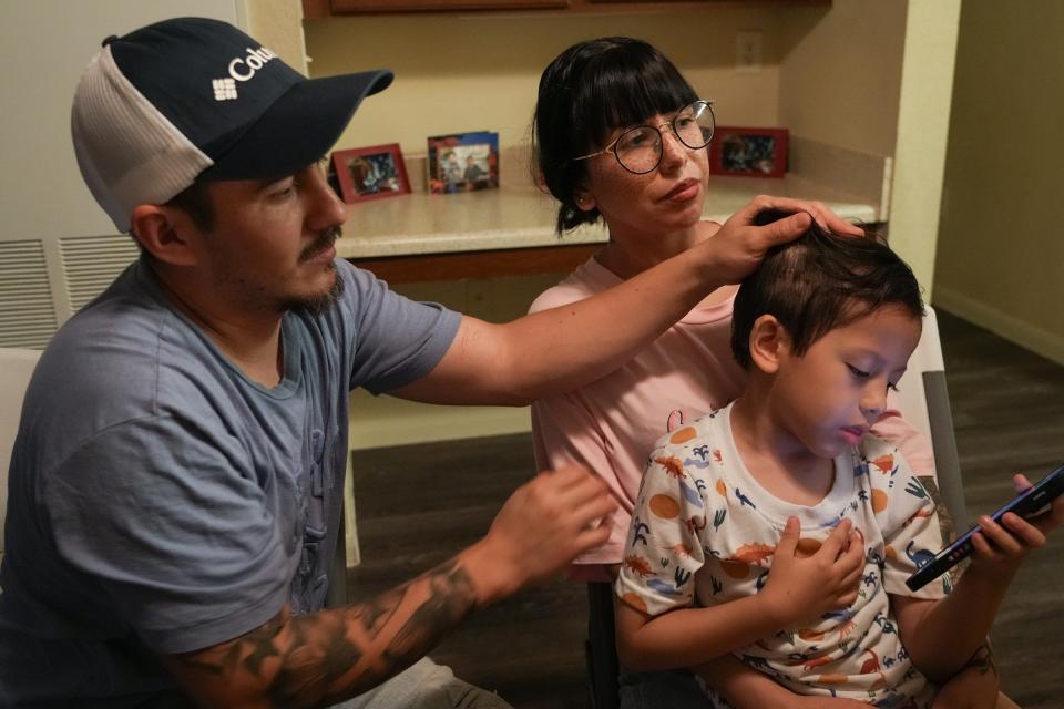 Christopher Reza, padre de Mauro Reza Flores, un sobreviviente de 5 años del accidente de autobús, le mueve el cabello hacia atrás para revelar su cicatriz del accidente mientras Jessica Flores, su madre, lo sostiene el 1 de mayo.