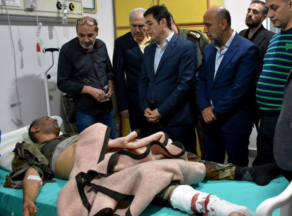 This photo released by the Syrian official news agency SANA shows Syrian Health Minister Hassan al-Ghabash, second left, checks a Syria soldier who was injured from a drone attack that hit a packed military graduation ceremony in the central city of Homs, Syria, Thursday, Oct. 5, 2023. Syria's health minister has raised the casualty tolls from a drone attack that hit a packed military graduation ceremony to 80 killed and 240 wounded. It was one of the deadliest attacks on the Syrian army recently, with its conflict now in its thirteenth year. (SANA via AP)