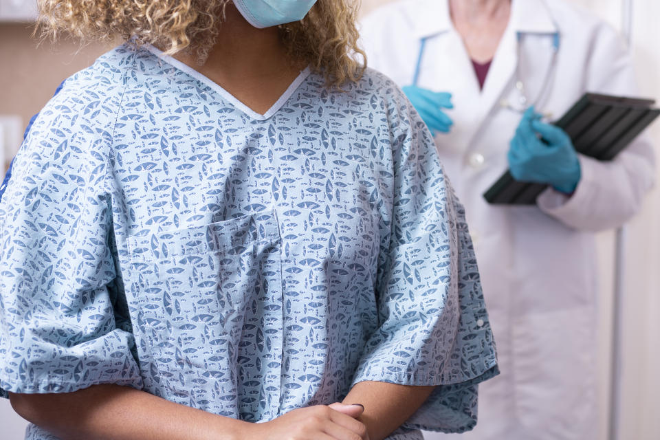 A young Black woman prepares for a breast exam and mammogram from her gynecologist.