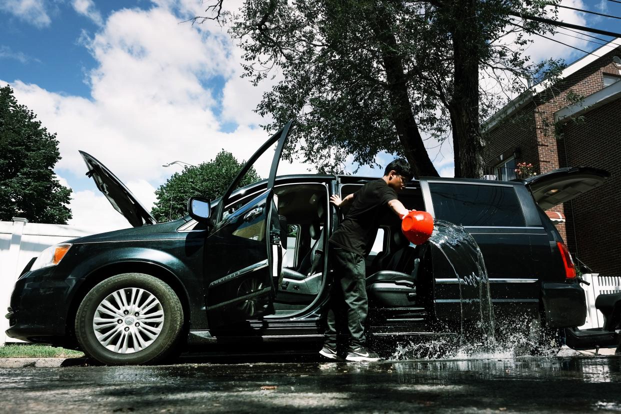 A teenager cleans water out from a car in a flooded Queens neighborhood that saw massive flooding and numerous deaths following a night of heavy wind and rain from the remnants of Hurricane Ida on Sept. 3, 2021 in New York City.