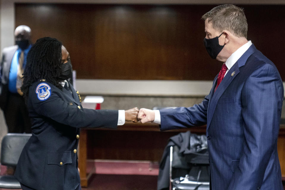 Former U.S. Capitol Police Chief Steven Sund, right, and Capitol Police Captain Carneysha Mendoza, left, greet each other before they testify before a Senate Homeland Security and Governmental Affairs & Senate Rules and Administration joint hearing on Capitol Hill, Washington, Tuesday, Feb. 23, 2021, to examine the January 6th attack on the Capitol. (AP Photo/Andrew Harnik, Pool)