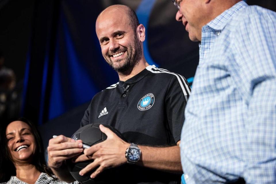 Charlotte FC’s new Head Coach Miguel Ángel Ramírez smiles as he signs a ball at a press conference in Charlotte Thursday. The team’s owner, David Tepper, is at right.