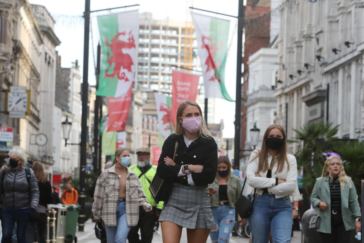 People wearing masks because of the coronavirus pandemic are seen in the center of Cardiff on Oct. 23, 2020, hours before Wales goes into a two-week lockdown.