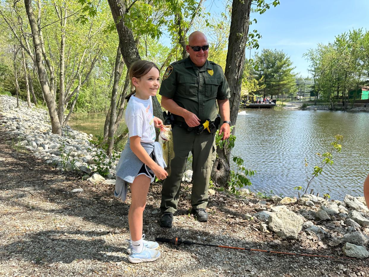 Ava Jones, a second-grade student from Mintonye Elementary, holds her largemouth bass alongside DNR conservation officer Matt Tholen on Thursday, Mary 2.