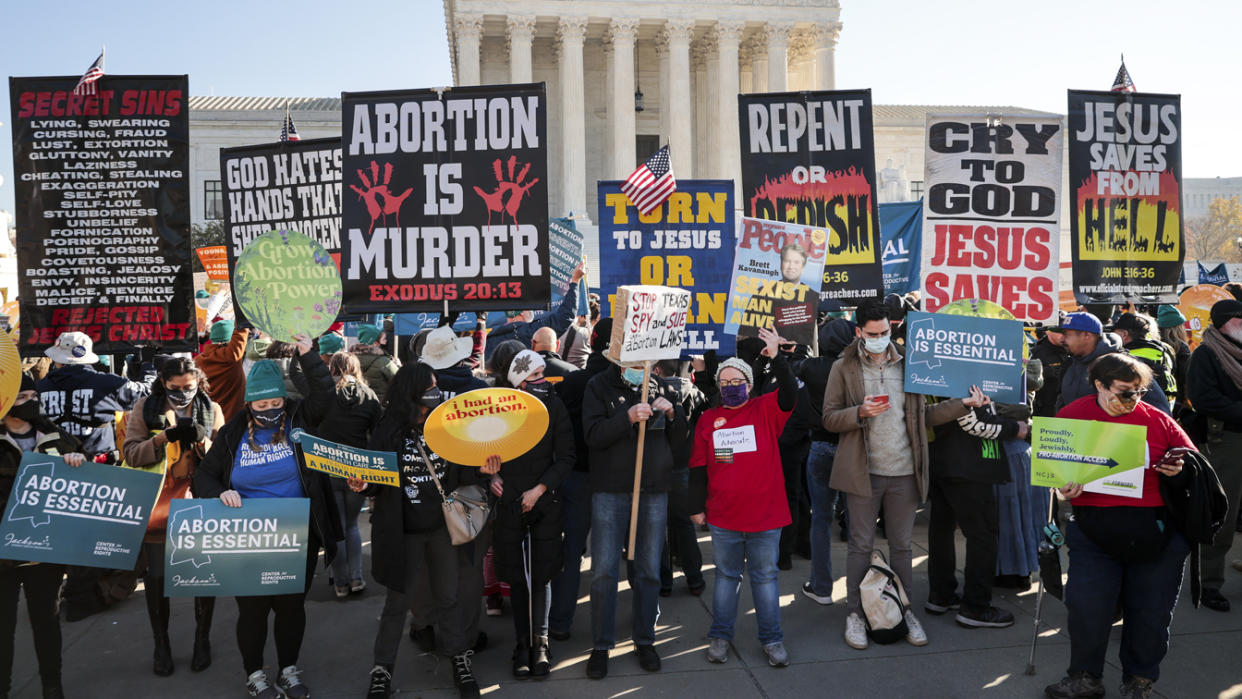 Demonstrators holding large signs gather in front of the U.S. Supreme Court as the justices hear arguments in Dobbs v. Jackson Women's Health, a case about a Mississippi law that bans most abortions after 15 weeks, on Wednesday. 