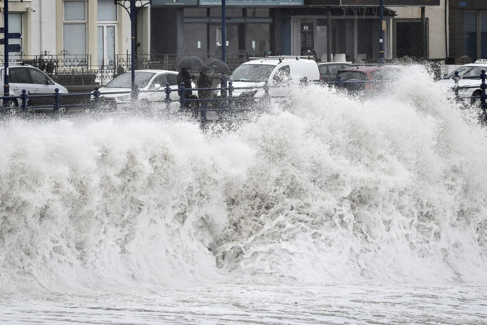 People watch waves pound against the harbour wall at Porthcawl in Wales, as Storm Dennis sweeps across the country, Saturday Feb. 15, 2020. Enormous waves are churning across the North Atlantic as Britain braces for a second straight weekend of wild winter weather and flooding. (Ben Birchall/PA via AP)