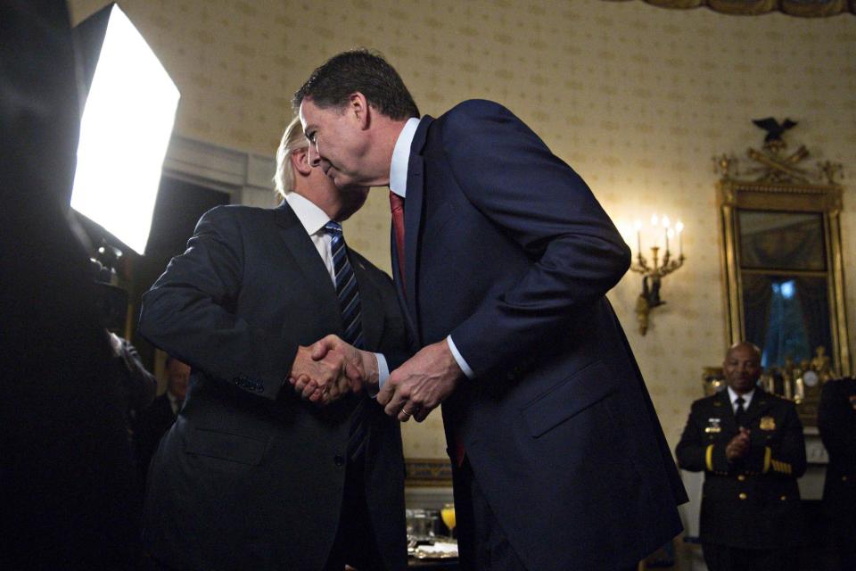 U.S. President Donald Trump (L) shakes hands with James Comey, director of the Federal Bureau of Investigation (FBI), during an Inaugural Law Enforcement Officers and First Responders Reception in the Blue Room of the White House on January 22, 2017 in Washington, DC. (Photo by Andrew Harrer-Pool/Getty Images)