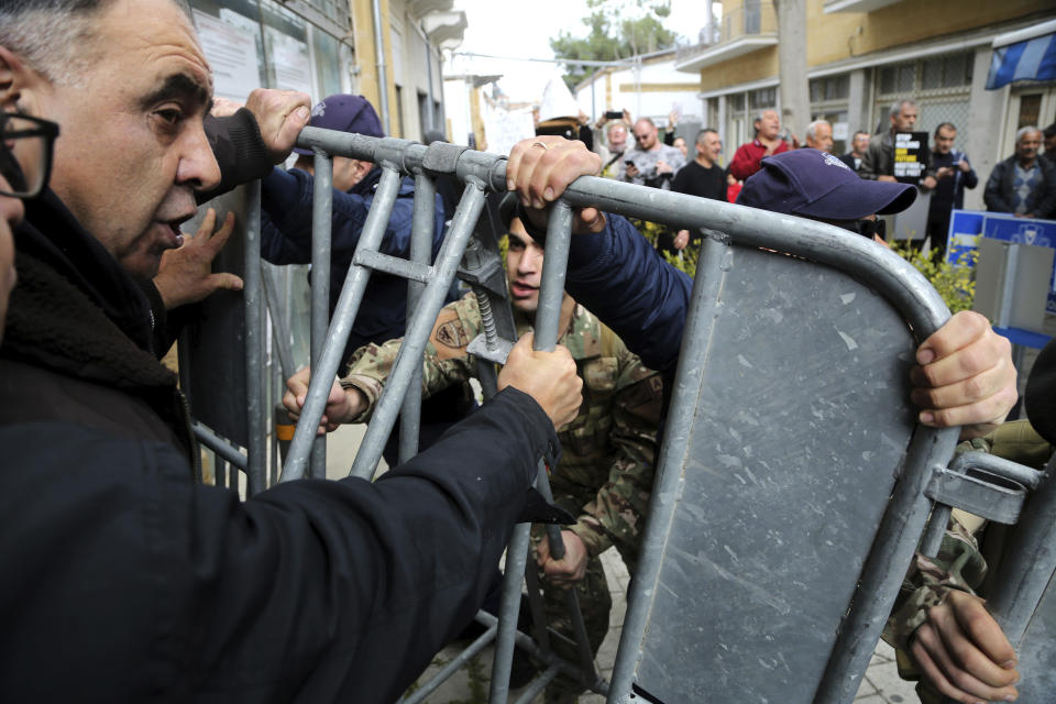 Protesters pull the barriers set up by the police as they demonstrate against the closing of a crossing point straddling a United Nations-controlled buffer zone in divided capital Nicosia, Cyprus, Saturday, Feb. 29, 2020. Around 200 people gathered at the Ledra Street crossing point to voice their opposition to it closing. The Cyprus government said it closed the Ledra Street crossing point along with three others to help with efforts to prevent the possible spread of a new COVID-19 virus either to the breakaway, Turkish Cypriot north or the internationally recognized, Greek Cypriot south. (AP Photo/Petros Karadjias)