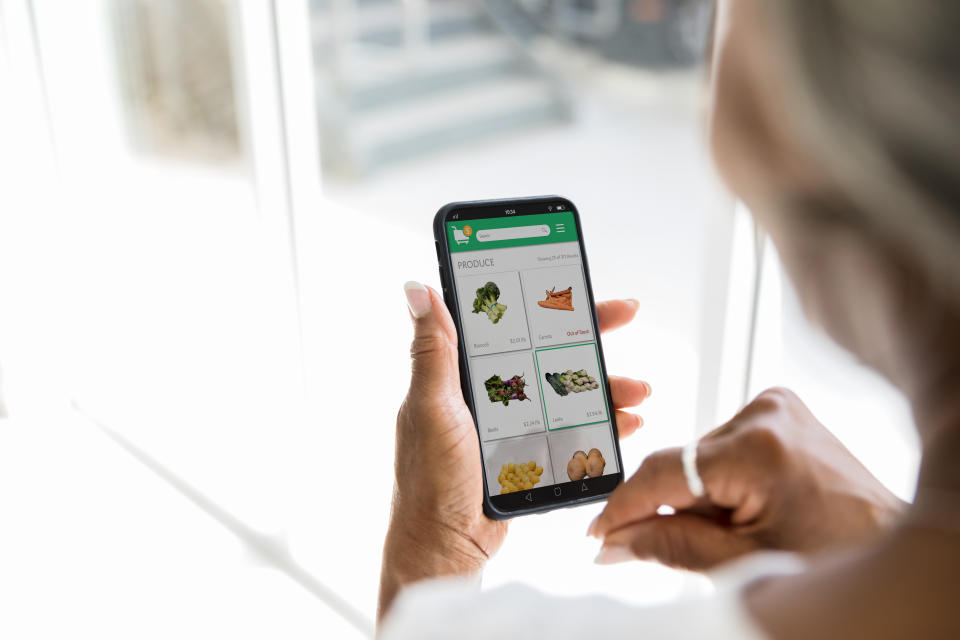 A woman uses a grocery delivery app on her smartphone