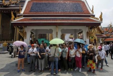 Chinese tourists listen to their guide as they visit Wat Phra Kaeo (Emerald Buddha Temple) in Bangkok March 23, 2015. REUTERS/Chaiwat Subprasom