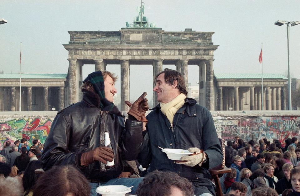 Two Berliners chat in front of Brandenburg Gate in Berlin on Nov. 12, 1989, while having lunch on a visitor's platform near the Berlin Wall.