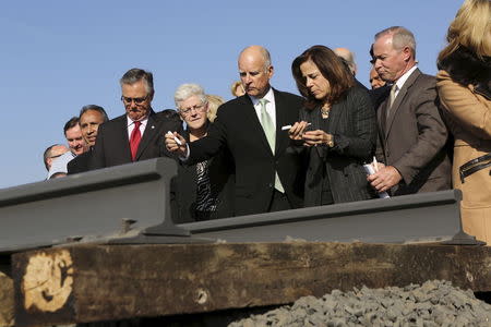 California Governor Jerry Brown (C) and his wife, Anne Gust, prepare to sign a railroad rail during a ceremony for the California High Speed Rail in Fresno, California in this January 6, 2015 file photo. REUTERS/Robert Galbraith