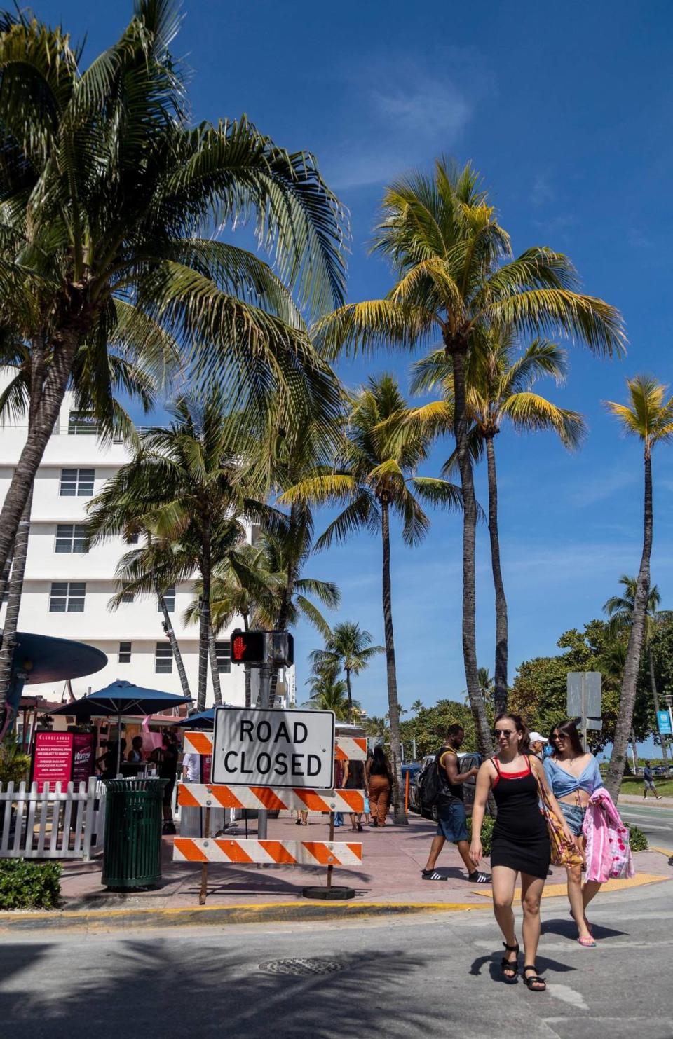 Two women walk past a “road closed” sign on the corner of 10th Street and Ocean Drive in Miami Beach on Feb. 29, 2024.