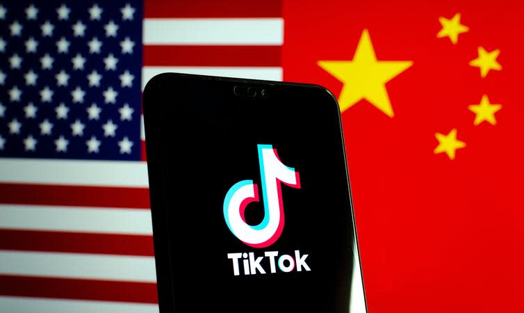 Phone showing TikTok in front of US and China flags.