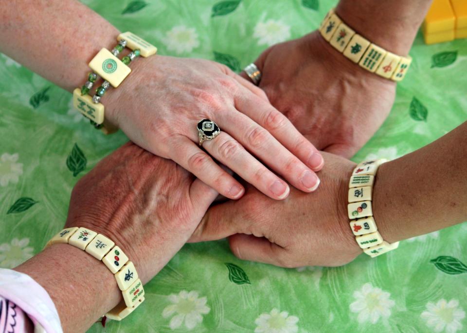 This May 31, 2013 photo shows women displaying bracelets made of mahjong pieces during a game night gathering in Mayfield Village, Ohio. For the baby boomer generation, getting together to play games is a way to stay active and social. It also can help people stay mentally sharp. (AP Photo/Bonnie Gruttadauria)