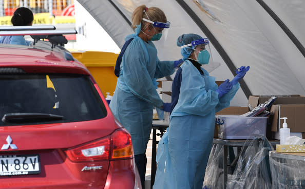 Healthcare workers wearing face shields and protective clothing are seen preparing to test people for COVID-19 at a pop-up testing clinic in Bondi Beach.