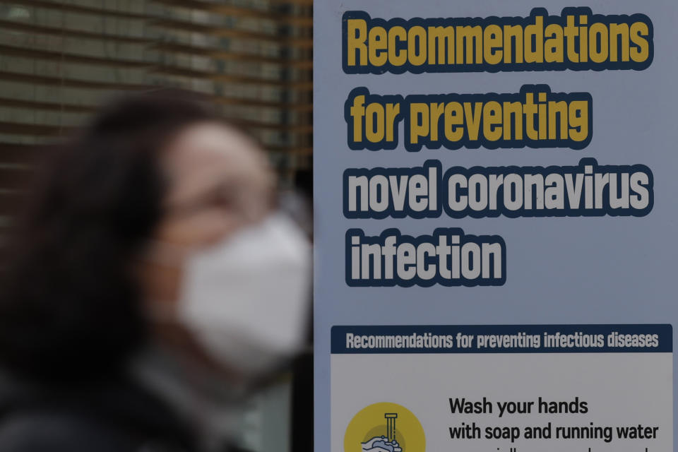 A woman wearing a face mask walks by a banner showing precautions against the coronavirus in downtown Seoul, South Korea, Thursday, Nov. 26, 2020. (AP Photo/Lee Jin-man)