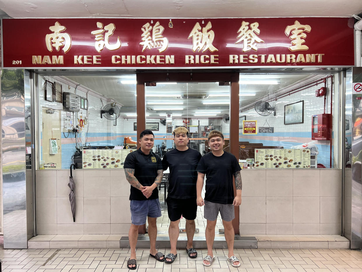 Image of the three Nam Kee brothers, who are third generation owners of the chicken rice brand, standing outside their Upper Thomson outlet.