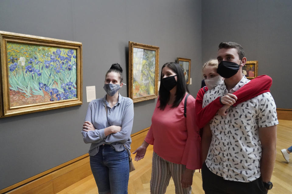 FILE - In this Wednesday, May 26, 2021 file photo, visitors wear masks as they view art, including Vincent van Gogh's "Irises", at left, at the newly re-opened Getty Center amid the COVID-19 pandemic in Los Angeles. Los Angeles County residents are again required to wear masks indoors regardless of their vaccination status, a new mandate starting this weekend that health officials hope will reverse the latest spikes in coronavirus cases, hospitalizations and deaths. The rule went into effect late Saturday, July 17, for the nation's largest county, home to 11 million people, where a sharp increase in COVID-19 cases is led by the highly transmissible delta variant. (AP Photo/Marcio Jose Sanchez, File)