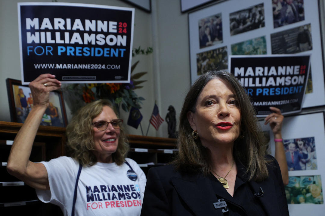 Marianne Williamson stands next to a supporter who holds a sign reading: Marianne Willamson for president.