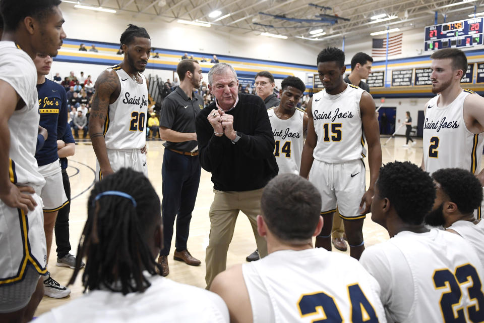 Saint Joseph coach Jim Calhoun, center, talks to his team during a timeout in the first half of an NCAA college basketball game against Pratt Institute, Friday, Jan. 10, 2020, in West Hartford, Conn. Now coaching Division III basketball with the same fire he stalked the sidelines at UConn, Calhoun is reaching his 900th win as a college coach. (AP Photo/Jessica Hill)