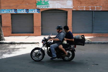 People ride on a motorcycle past the Los Cotorros club where several people died when a person activated a tear gas grenade inside, according to Venezuela's interior minister Nestor Reverol, in Caracas, Venezuela June 16, 2018. REUTERS/Marco Bello