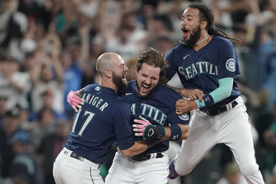 Seattle Mariners' Luis Torrens, center, is greeted by teammates Mitch Haniger, left, and J.P. Crawford, right, after Torrens hit a walk-off RBI single to give the Mariners a 1-0 win over the New York Yankees in a 13-inning baseball game, Tuesday, Aug. 9, 2022, in Seattle. (AP Photo/Ted S. Warren)