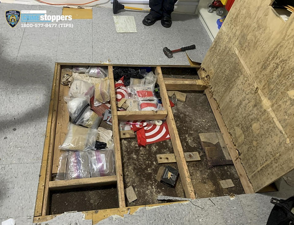 In this photo provided by the New York City Police Department, a trap door leans open over narcotics, including fentanyl, and drug paraphernalia stored in the floor of a day care center, Thursday, Sept. 21, 2023, in New York. Police say the owners of the New York City day care center where a toddler died and three others were sickened by opioid exposure the week before were hiding the bags of fentanyl concealed by plywood and tile flooring. (Courtesy NYPD via AP)