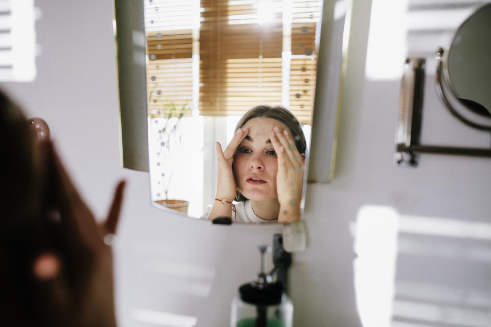 Frau schaut sich im Spiegel an (Symbolbild: Getty Images)