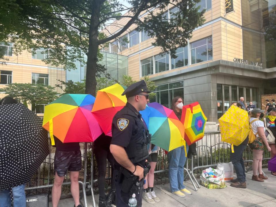 Defenders of drag queen story hour hold up rainbow umbrellas to ward off right-wing protesters. 
